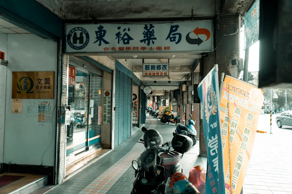 Motorcycles parked under an arcade in an urban street with Asian signage and closed shops.