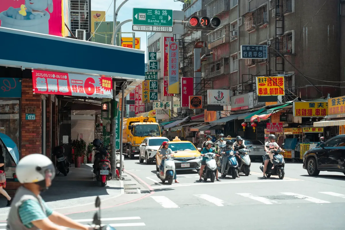 台湾の台北で、スクーター、自動車、そして色鮮やかな看板が輝くにぎわいの通り。