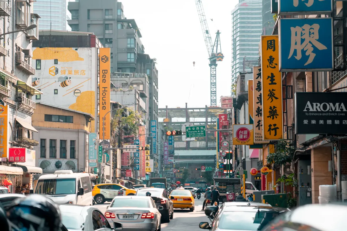 台湾の台北で、交通がにぎわい、色とりどりの看板がそそぐ都会の通り。