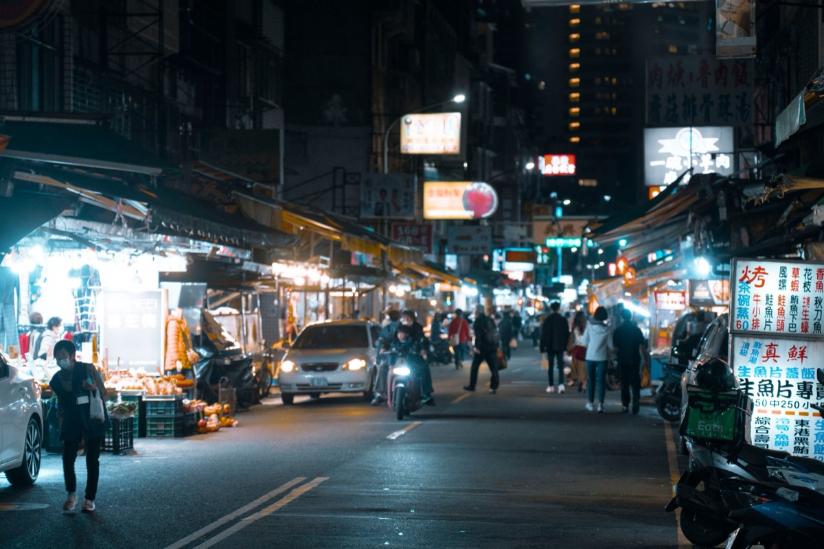 Barracas coloridas de um mercado noturno em Taiwan com comida fumegante.